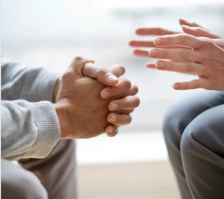 Person sat opposite another person with their hands clasped together