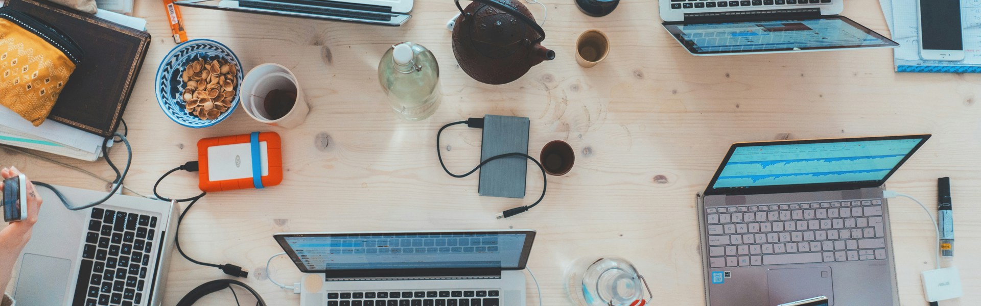 People sitting down near table with assorted laptop computers